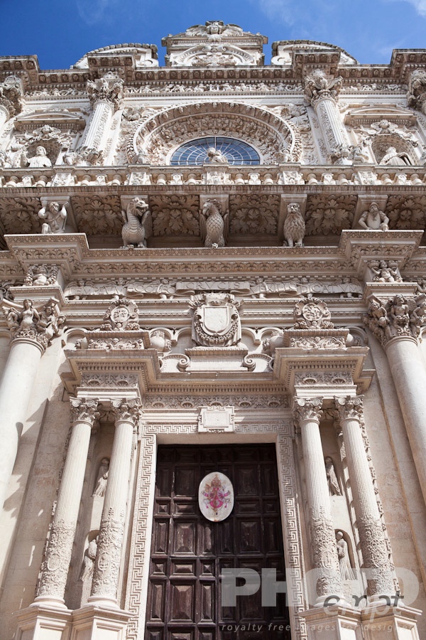 Italy South - Puglia. . . . . Facade of church of Santa Croce, exuberant Baroque ornamentation of facade with rose window, as seen from below, sunny spring morning with blue sky, Lecce, Salento, Puglia, Southern Italy