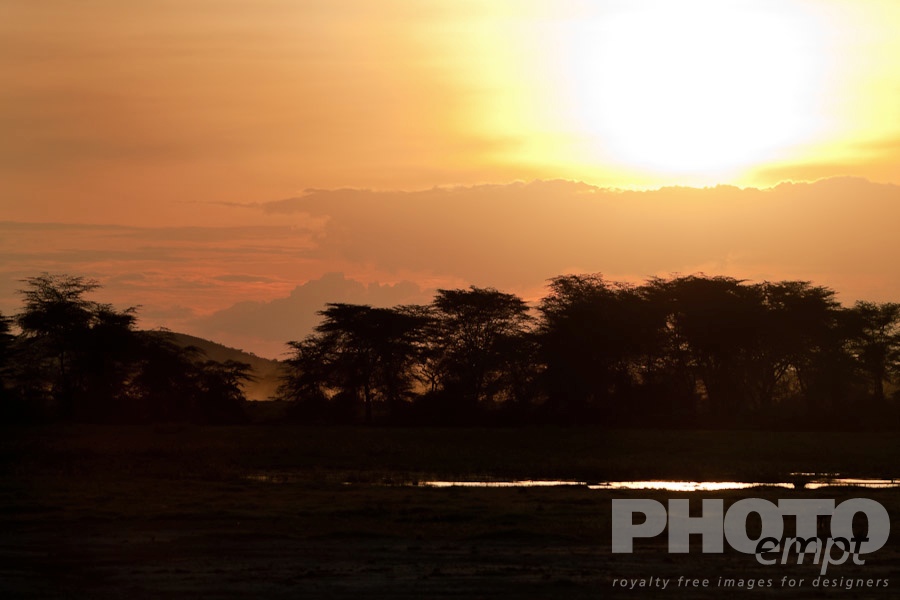 African Safari - Kenya. . . . . Beautiful African sunset, savannah with marshland, water reflecting colours of sky, trees silhouetted, and mountains beyond, Kenya, Africa