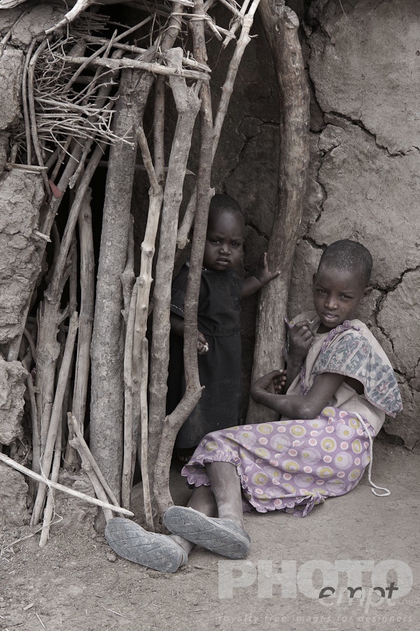 African Safari - Kenya. . . . . Desaturated view of two Masai children: approx 3 year old boy and 8 year old girl, at entrance to traditional mud house, Masai village, Kenya, Africa