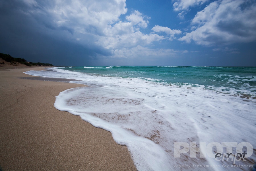 Italy South - Puglia. . . . . Empty, fine sandy beach with white foam of rough sea, green sea colour, blue sunny sky, with storm threatened,  Salento, Puglia, Southern Italy
