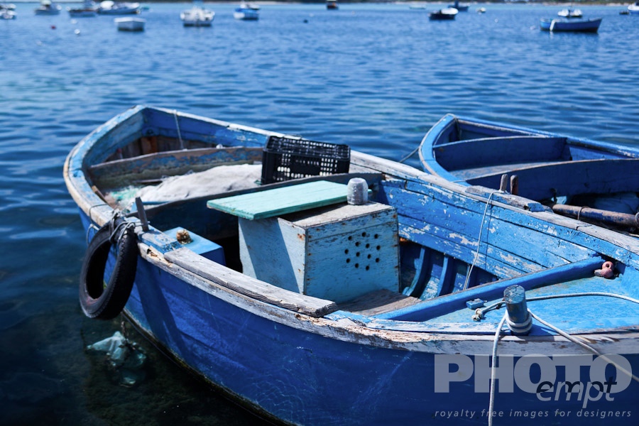 Italy South - Puglia. . . . . Close up view of wooden painted blue fishing boats moored, with view of other boats in background, Porto Cesareo harbour, sunny spring morning, Salento, Puglia, Southern Italy