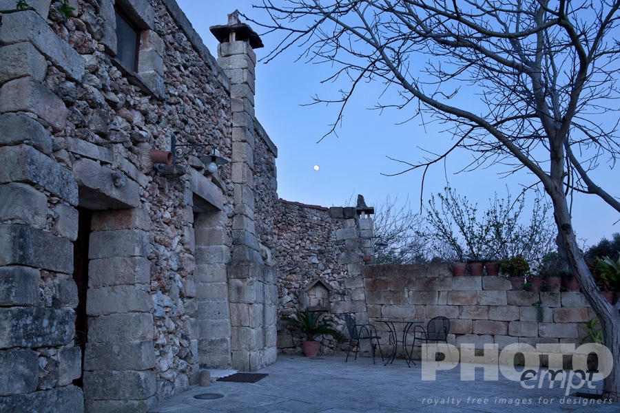 Italy South - Puglia. . . . . Typical stone farmhouse building, detail from side  of entrance and courtyard at twilight with full moon rising, Salento, Puglia, Southern Italy