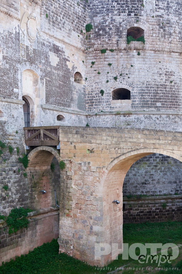 Italy South - Puglia. . . . . Detail of 16th century castle, with bridge leading across grassed moat to stone wall and round tower, Otranto, Salento, Puglia, Southern Italy