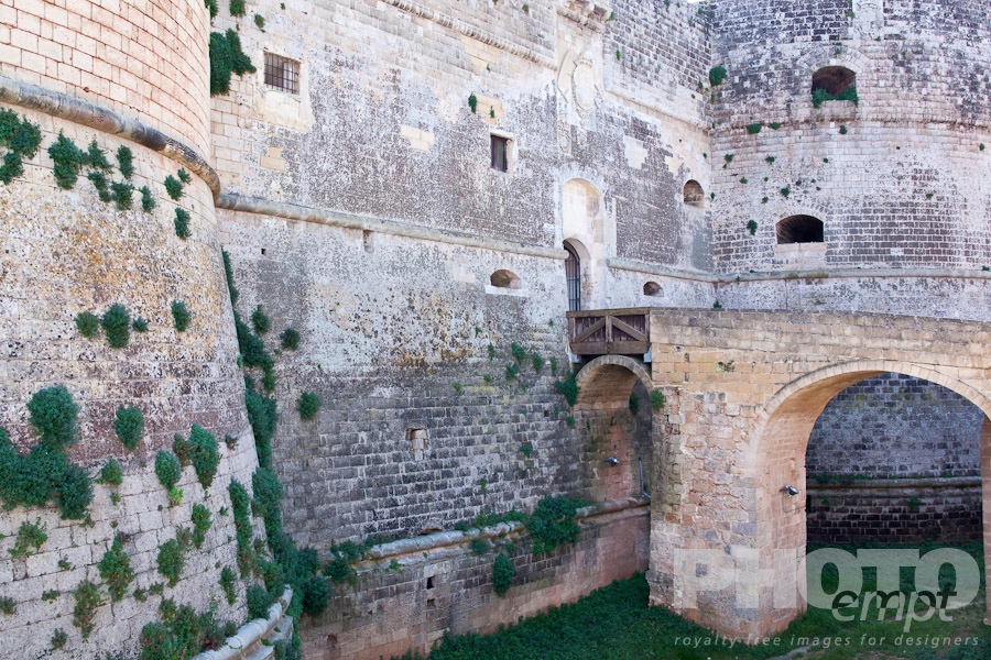 Italy South - Puglia. . . . . Detail of 16th century castle, with bridge leading across grassed moat to stone wall and round tower, Otranto, Salento, Puglia, Southern Italy