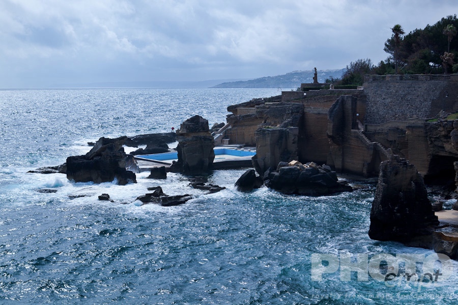 Italy South - Puglia. . . . . Coastline on sunny afternoon with storm threatened, rocky cliffs, walls and stairways to open thermal baths of Santa Cesarea Terme, lone figure on rocks, Salento, Puglia, Southern Italy