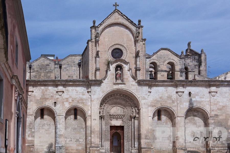 Italy South - Puglia. . . . . View of Romanesque facade of church of San Giovanni, with typical stone carved scroll work and statues, arched loggia, sunny spring afternoon with blue sky, Matera, Puglia, Southern Italy