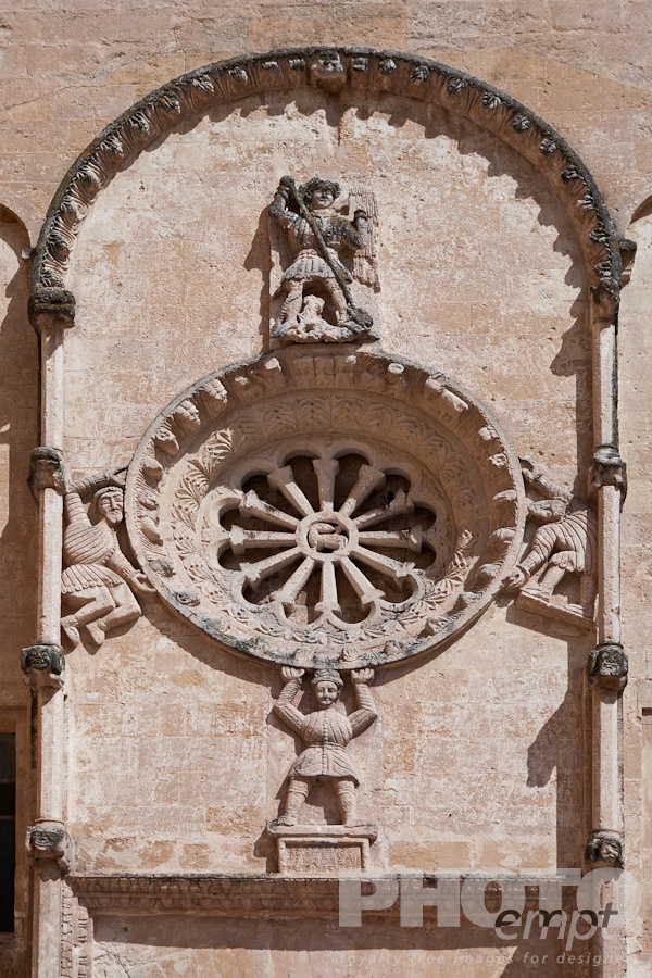 Italy South - Puglia. . . . . Detail of Romanesque facade of church of San Domenico, with typical stone carved scroll work and statues around rose window, sunny spring afternoon, Matera, Puglia, Southern Italy