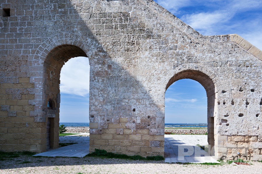 Italy South - Puglia. . . . . Detail view of Torre Lapillo, 16th century tower coastline defense, with coastline framed by arched stairway leading to square stone tower, sunny spring morning, Salento, Puglia, Southern Italy