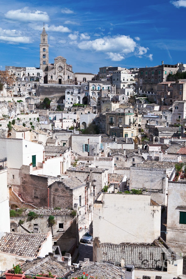 Italy South - Puglia. . . . . Aerial view of ancient town of Matera with tufa houses, and Duomo on hill beyond, sunny spring afternoon with blue sky, Puglia, Southern Italy,