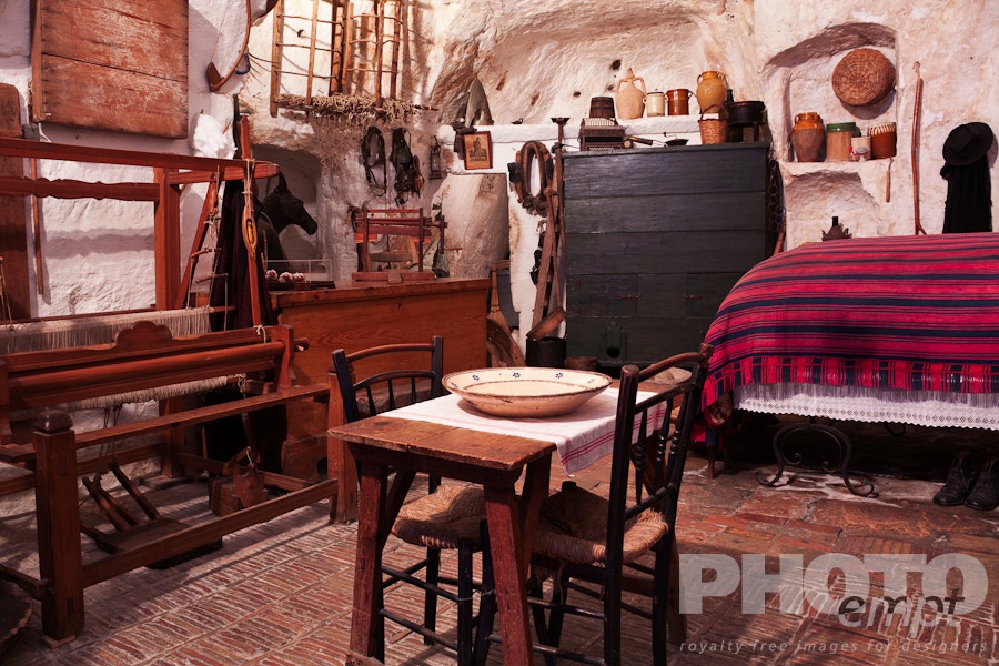 Italy South - Puglia. . . . . Interior of house built into tufa cavern, showing bed, table, chairs, weaving loom , and antique implements representational of traditional life in Matera, Puglia, Southern Italy