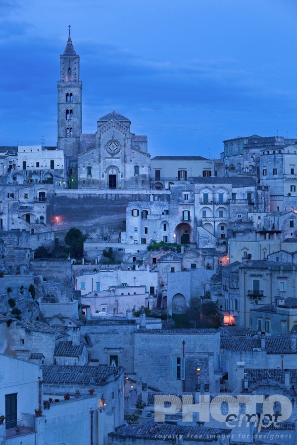 Italy South - Puglia. . . . . Aerial view of ancient town of Matera with tufa houses, Duomo and Campanile on hill beyond, at dusk with night illumination, Puglia, Southern Italy,