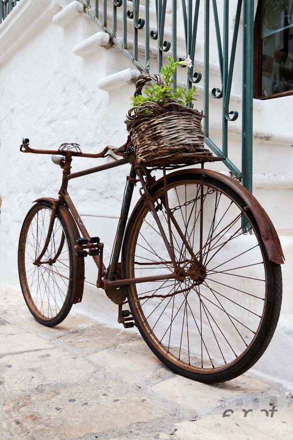 Italy South - Puglia. . . . . Street detail in Ostuni, with typical white stucco walls, stone paving, metal bicycle chained to wrought iron railing of stairway, with wicker basket of flowers on back, spring afternoon, Salento, Puglia, Southern Italy