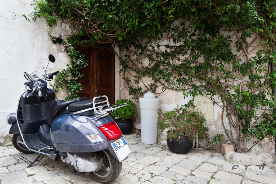 Italy South - Puglia. . . . . Street detail in Ostuni, with typical white stucco walls, stone paving,motorbike parked outside doorway, spring afternoon, Salento, Puglia, Southern Italy
