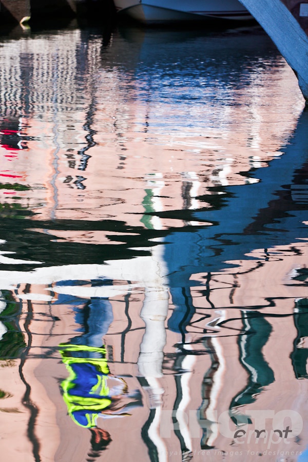 Venice in Autumn. . . . . Close up of canal reflection: arch of bridge with man walking across, wearing brightly coloured work jacket, sunny autumn morning in Venice, Northern Italy