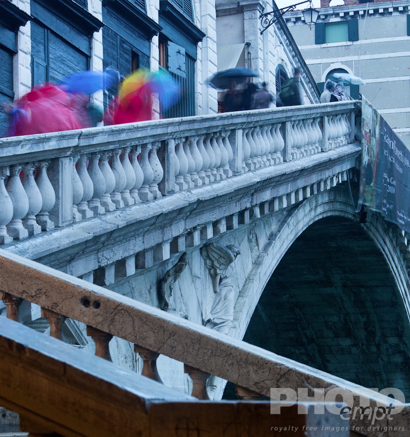 Venice in Autumn. . . . . Close up of Rialto Bridge from below, in rain at twilight, with motion blur of pedestrians on outer stairway, with bright red coats and multicoloured umbrellas, against white stone balustrade, Venice, Northern Italy